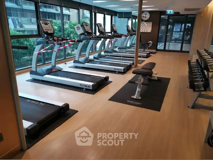 Modern gym with treadmills and weights in a sleek residential building.