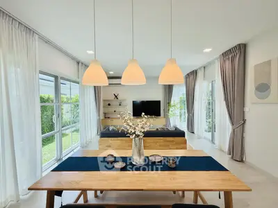 Modern living room with elegant dining area and garden view, featuring stylish lighting and decor.