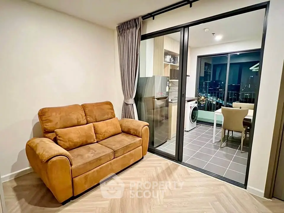 Modern living room with cozy sofa and open kitchen layout in high-rise apartment.