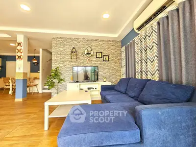 Spacious living room with modern decor and blue sofa, featuring stylish stone accent wall and open layout.