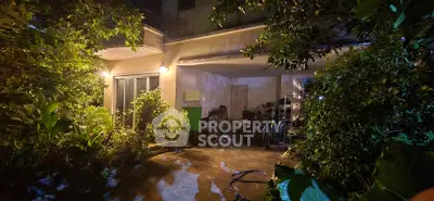 Charming night view of a lush garden entrance with ambient lighting and greenery.