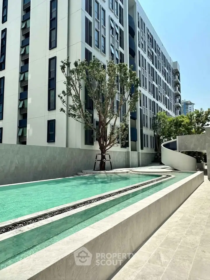 Modern apartment building with sleek pool and lush greenery, offering luxury urban living.