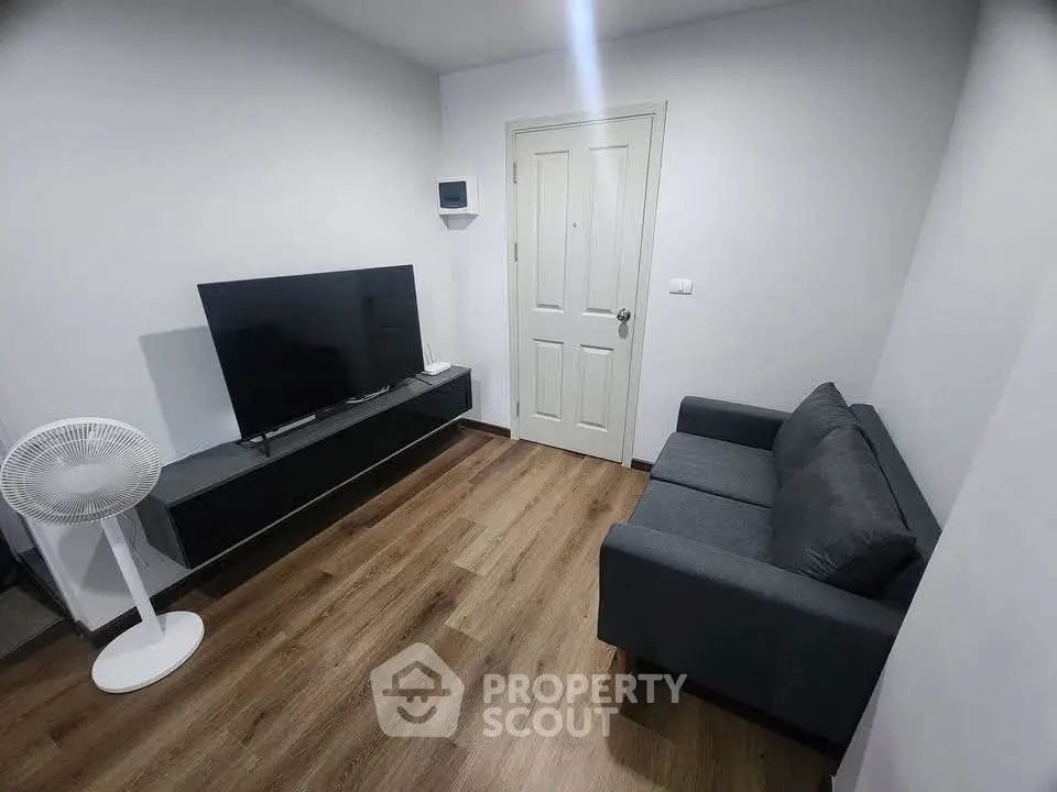 Modern living room with sleek TV setup and cozy gray sofa on wooden flooring.