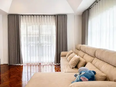 Spacious living room with elegant curtains and plush beige sofa, perfect for relaxation.