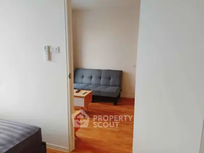 Cozy apartment interior with wooden flooring and modern furniture, featuring a stylish gray sofa and a small coffee table.