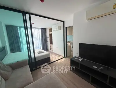 Modern studio apartment with glass partition, cozy living area, and sleek bedroom design.