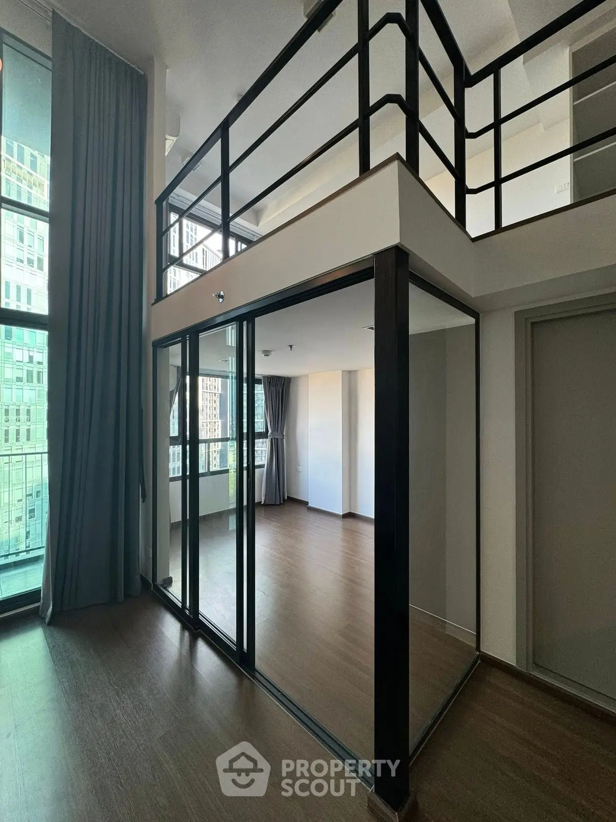 Modern loft apartment with glass walls and high ceilings in urban setting.