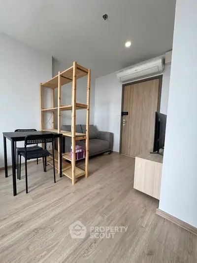 Modern living room with wooden flooring, minimalist furniture, and natural light.