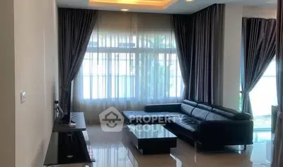 Elegant living room with modern black leather sofa and large windows