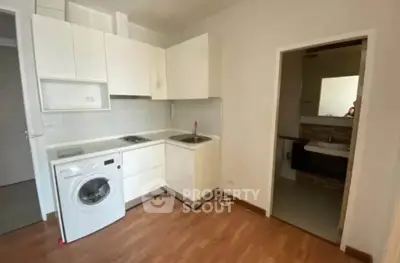 Compact kitchen with washing machine and adjacent bathroom in modern apartment.