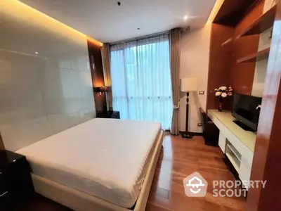 Modern bedroom with polished wooden floors, large bed, and built-in wooden cabinetry, offering a cozy and stylish living space.