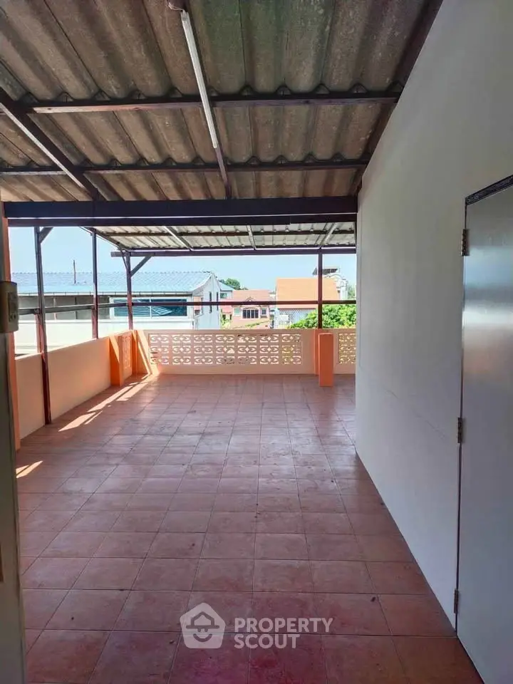 Spacious rooftop terrace with tiled flooring and partial roof cover, ideal for outdoor relaxation.
