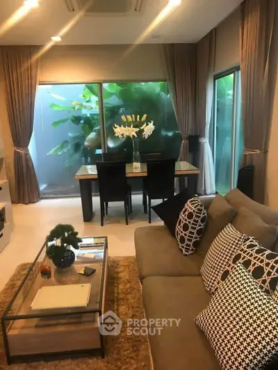 Stylish living room with modern decor and large windows overlooking lush greenery.