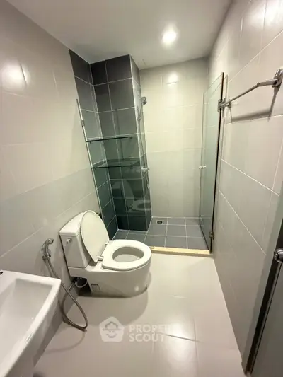 Modern bathroom with sleek design, featuring a glass shower enclosure and contemporary fixtures.
