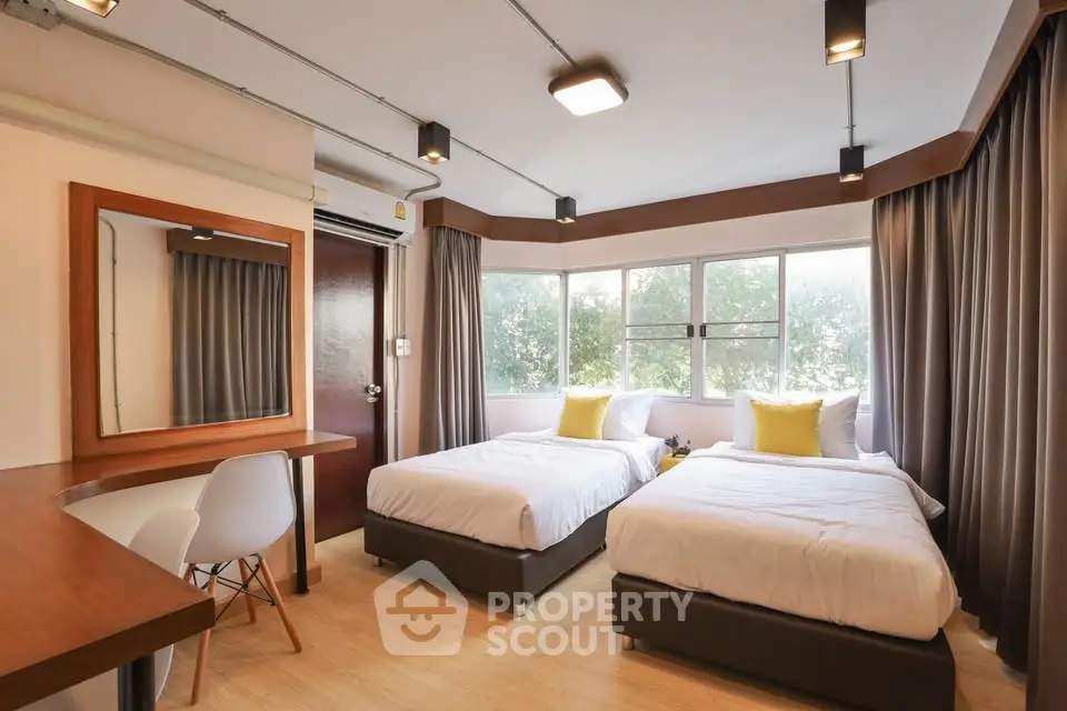 Modern bedroom with twin beds and large windows offering natural light.