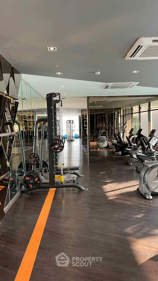 Modern gym with state-of-the-art equipment and mirrored walls in luxury residential building.