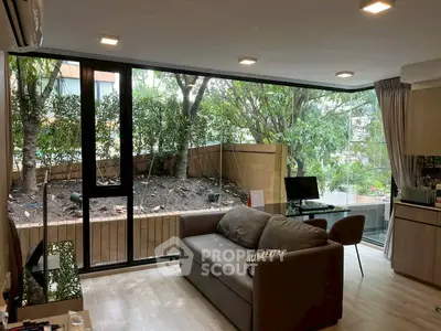 Modern living room with large windows and garden view, featuring cozy sofa and sleek decor.