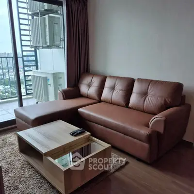 Modern living room with leather sofa and city view balcony in high-rise apartment.
