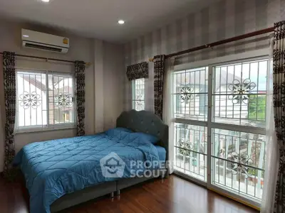 Spacious bedroom with large windows and elegant decor in a modern home.