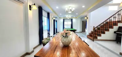 Spacious living room with elegant wooden dining table and stylish staircase in modern home.