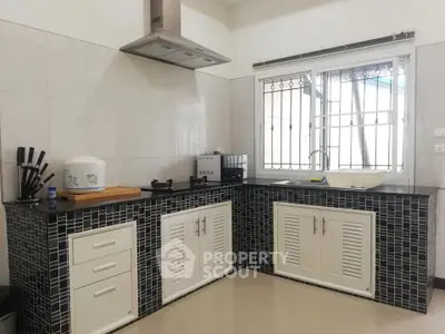 Modern kitchen with sleek black and white tile design, featuring gas stove and ample storage.