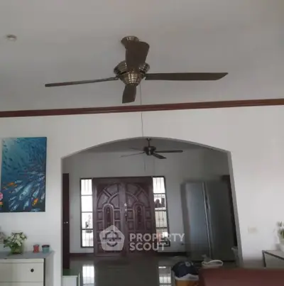 Spacious living area with ceiling fan and elegant wooden door