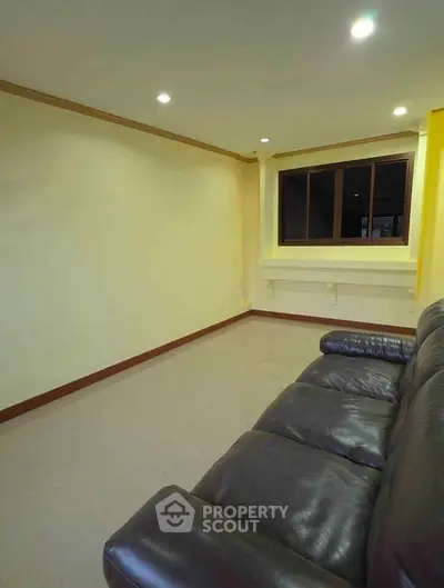 Spacious living room with leather sofa and large window, perfect for relaxation and entertainment.
