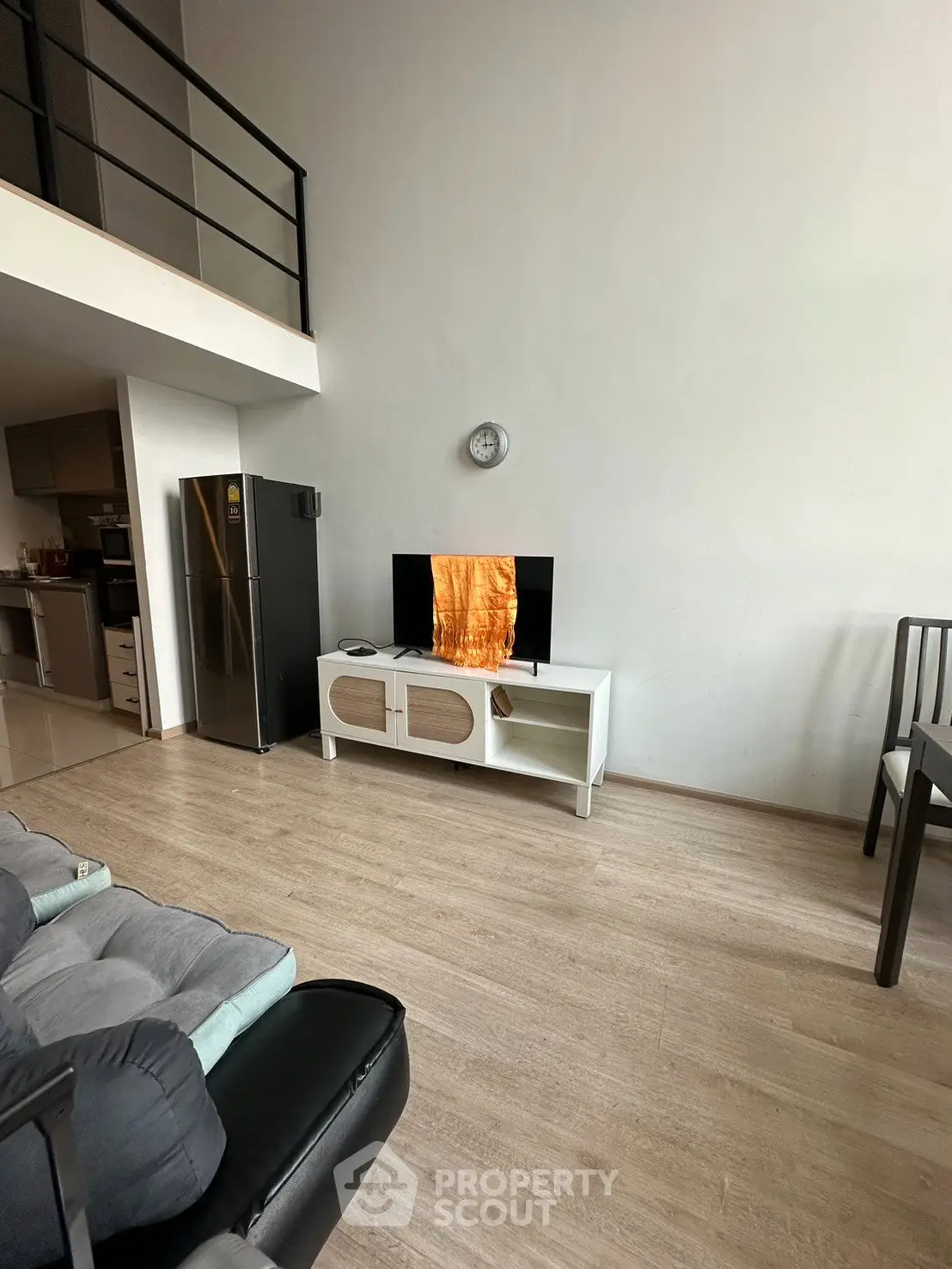 Modern living room with high ceiling, sleek furniture, and open kitchen layout in a stylish apartment.