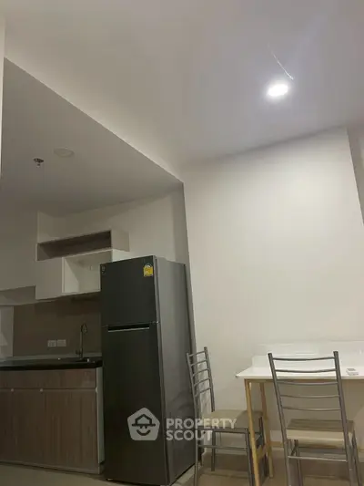 Modern kitchen with sleek fridge and dining area in a cozy apartment setting.