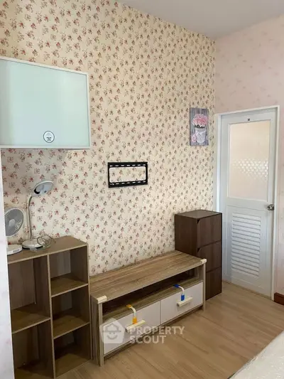Charming bedroom with floral wallpaper and modern wooden furniture, perfect for cozy living.