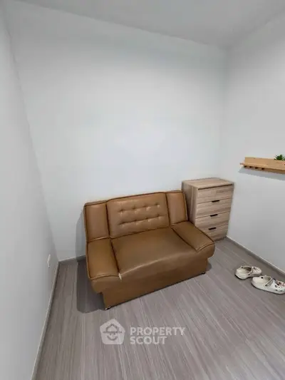 Cozy small living room with brown leather sofa and modern wooden furniture.