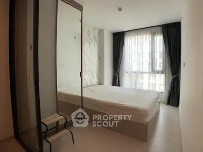Modern bedroom with large window and stylish decor in a contemporary apartment.