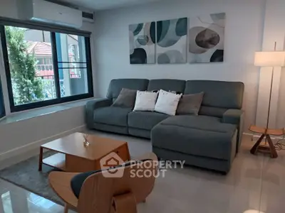 Modern living room with stylish furniture and large window offering natural light.