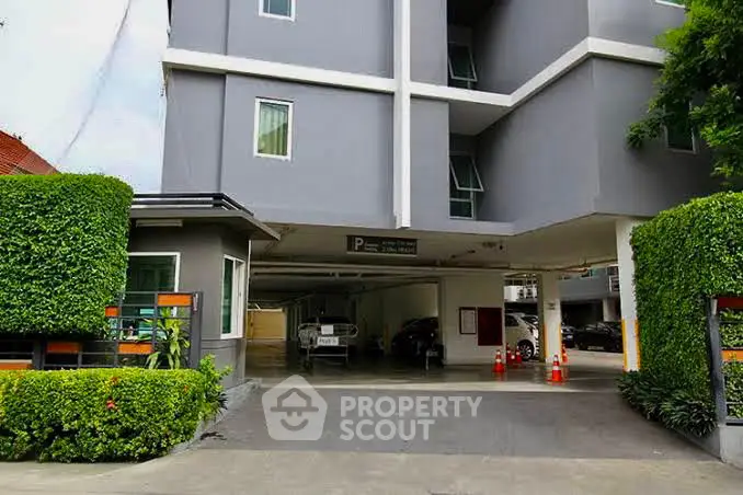 Modern apartment building with covered parking and lush greenery