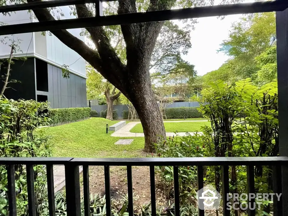 Serene garden view from modern apartment balcony with lush greenery and mature trees