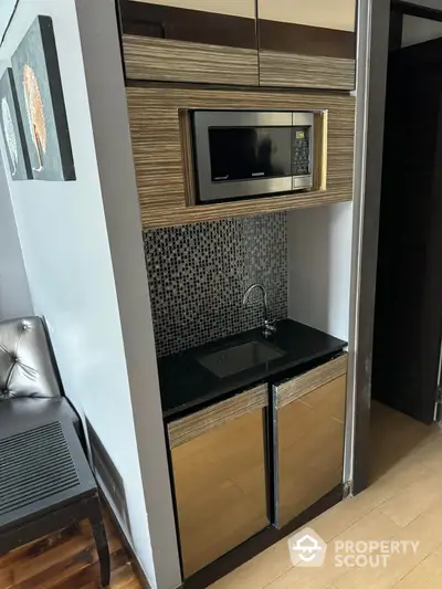 Compact modern kitchenette with microwave and sleek cabinetry