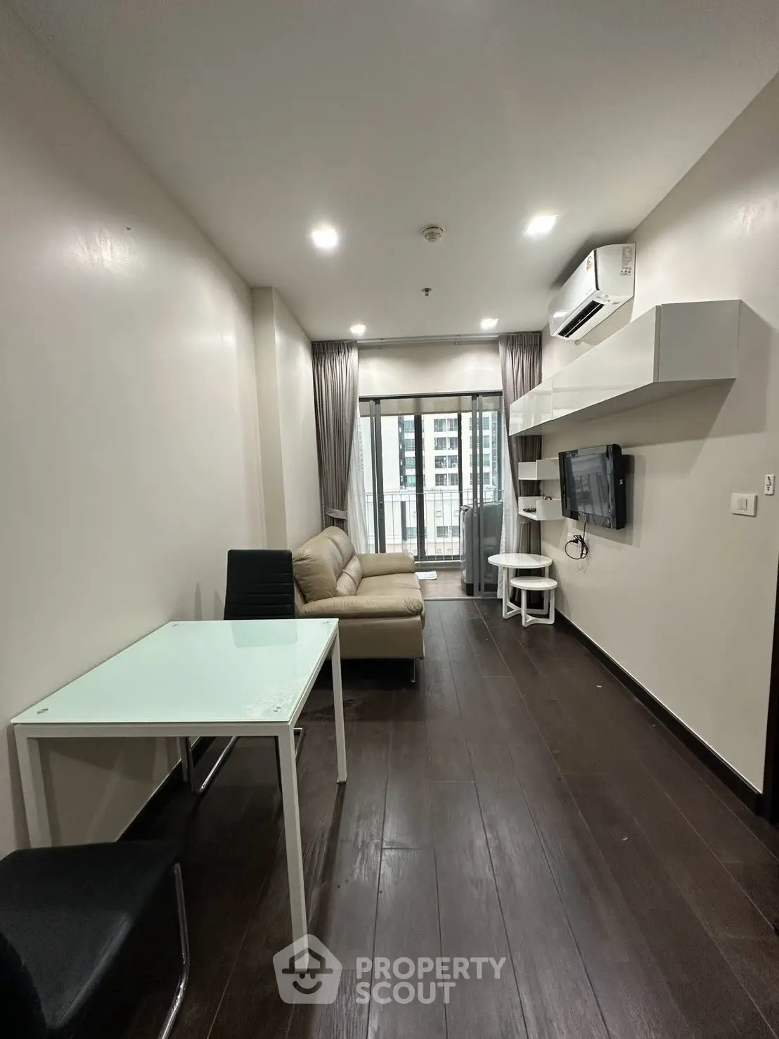 Modern living room with sleek furniture and city view balcony in a high-rise apartment.