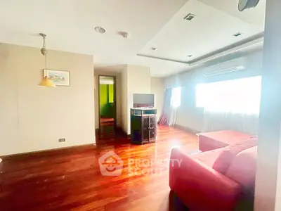 Spacious living room with hardwood floors and modern decor in a bright apartment.