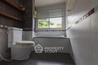 Modern bathroom with large window and stylish tile design.