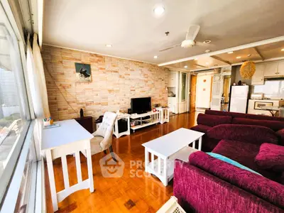 Spacious living room with modern decor and open kitchen layout, featuring large windows and stylish furniture.