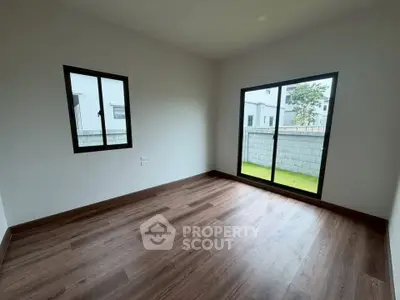 Spacious empty room with large windows and wooden flooring, perfect for customization.