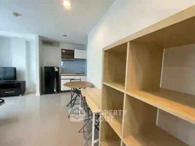 Modern apartment interior with open kitchen and dining area, featuring sleek furniture and ample storage.