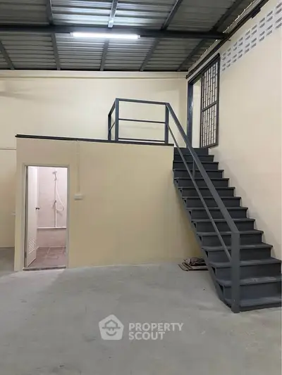 Industrial-style loft with staircase and high ceiling, perfect for creative workspace or urban living.