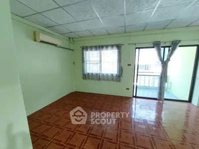 Spacious empty room with tiled floor and balcony access, ideal for customization.