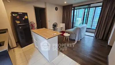 Modern open-layout living room with kitchen island and balcony view in urban apartment.