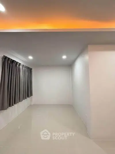 Spacious empty room with modern lighting and large window, perfect for customization.