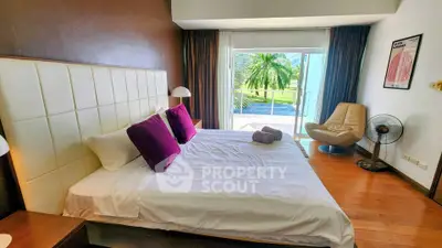 Spacious bedroom with modern decor and large window overlooking lush greenery.