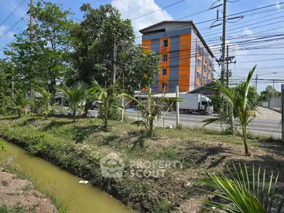 Modern orange apartment building with lush greenery and clear blue sky.