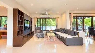 Spacious living room with modern furniture and large windows overlooking greenery.