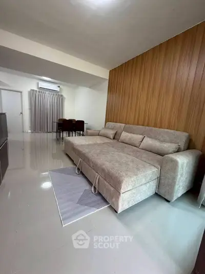 Spacious living room with modern sofa and elegant wood paneling, perfect for relaxation and entertainment.
